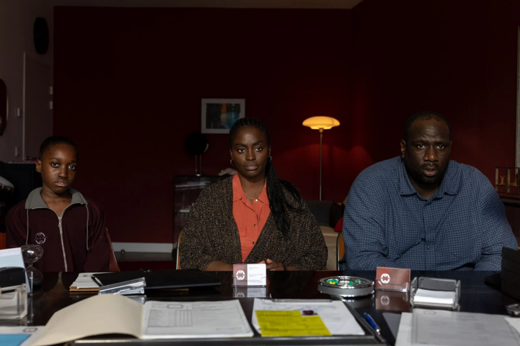 Oumy Bruni Garrel, Aïssa Maïga et Steve Tientcheu assis en rang sur une table dans le film Neneh Superstar