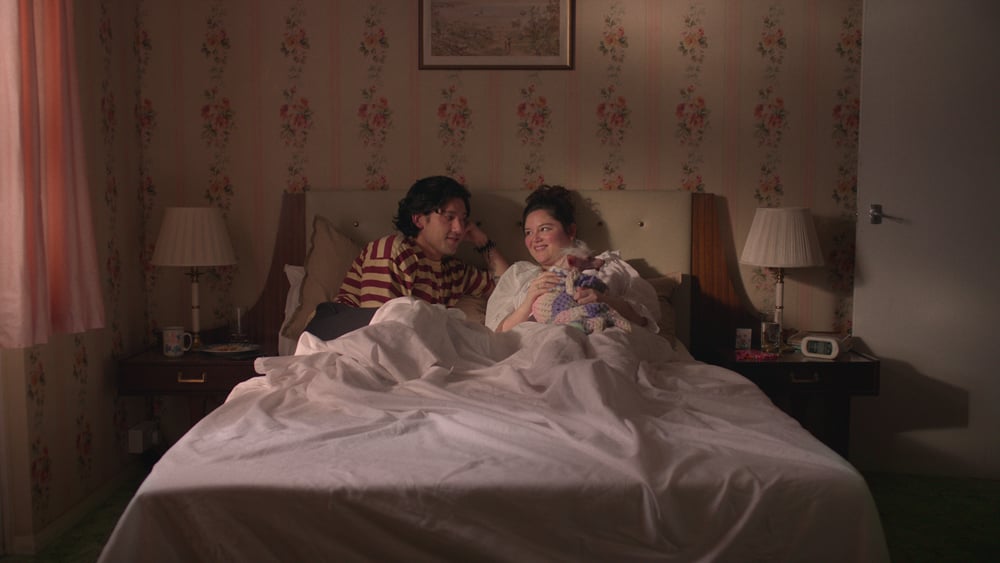 Photo de Will Sharpe et Megan Stalter, acteurs de la série Too Much, allongés dans un lit.