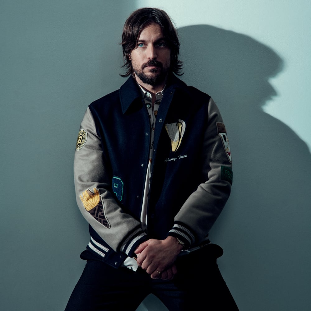 Lucas Bravo pour Numéro Homme. Blouson en laine brodée, chemise en soie imprimée et pantalon en drap de laine, Fendi. Montre et bague personnelles.