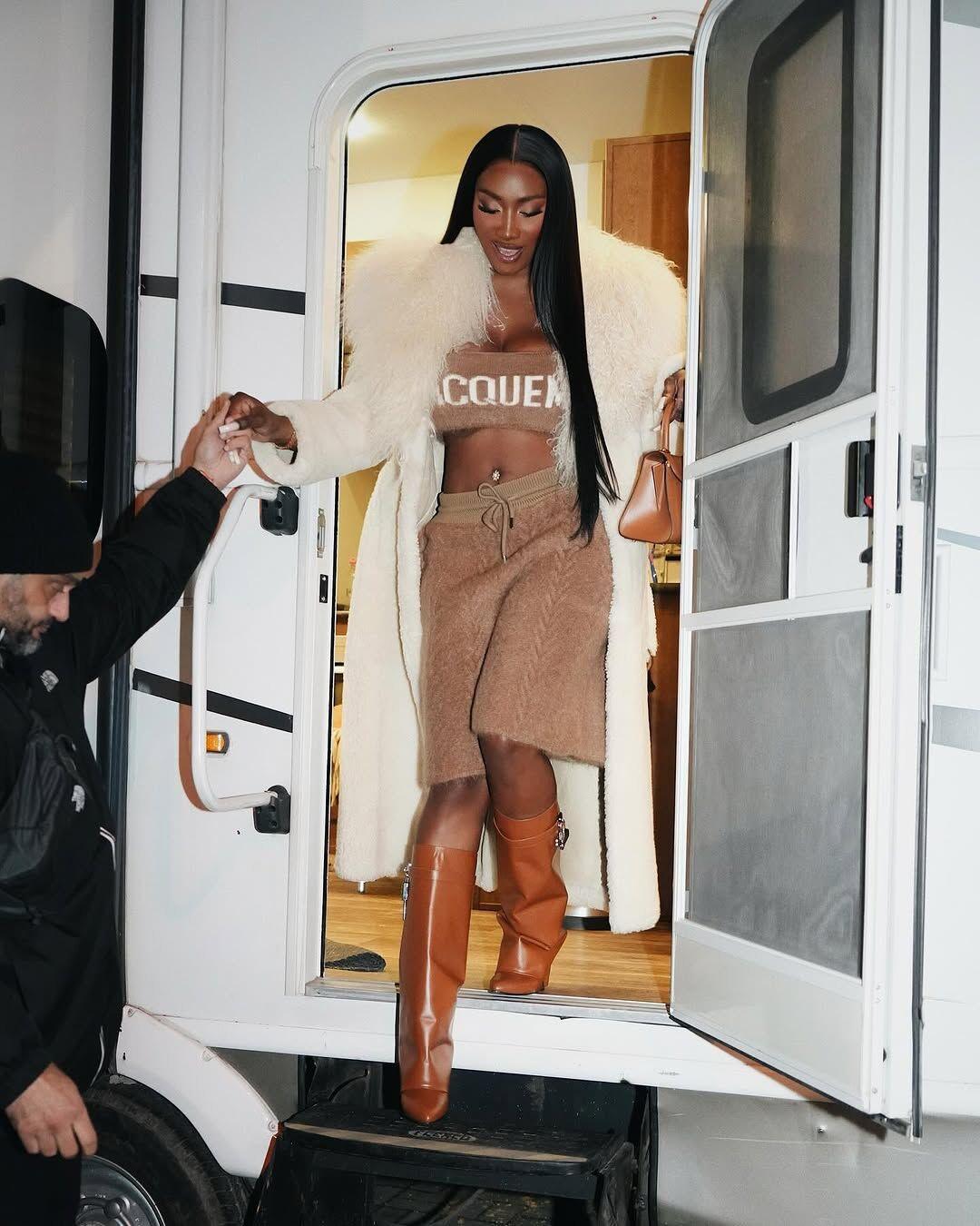 aya nakamura en top et short beige avec un manteau en fourure blanche et des bottes givenchy.