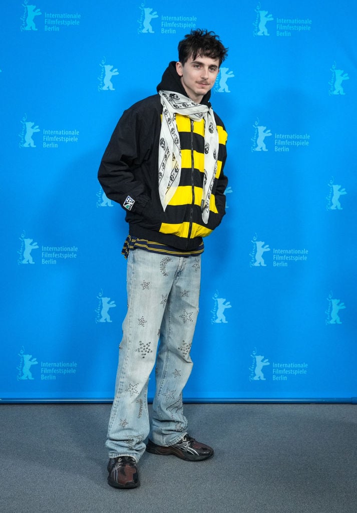 Timothée Chalamet en veste Adidas Columbus Crew, echarpe McQueen, jeans Kikunobu et baskets Asics, le 14 février 2025 à Berlin. © Photo by Soeren Stache/picture alliance via Getty Images.