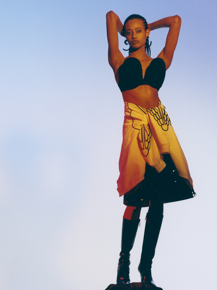Palmyre Tramini photographiée par Lee Wei Swee pour Numéro. Top Duran Lantink, jupe et culotte Prada, sweat Jordan x Paris Saint-Germain, bottes Amina Muaddi et boucles d'oreilles Hugo Kreit. 