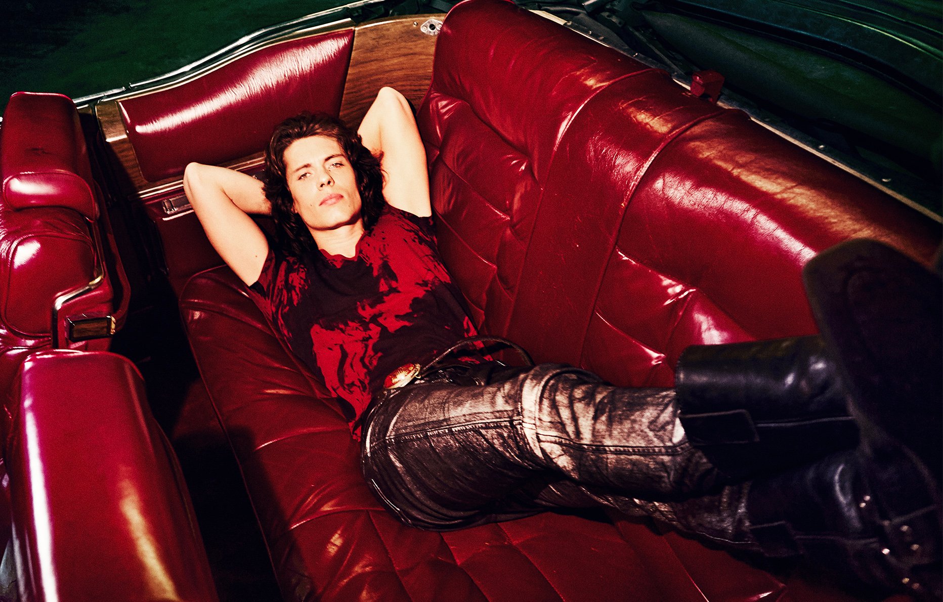 L'artiste Asphalt prend la pose allongé sur un canapé rouge, sélectionné dans les chanteurs à suivre selon Numéro © Elle Von Unwerth.