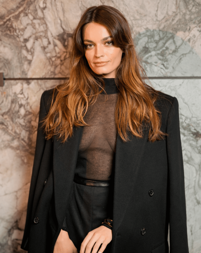 À l'affiche du film Le Monde de Narnia, l'actrice Emma Mackey prend la pose sur le photocall d'un défilé dans un costume noir et top en dentelle.