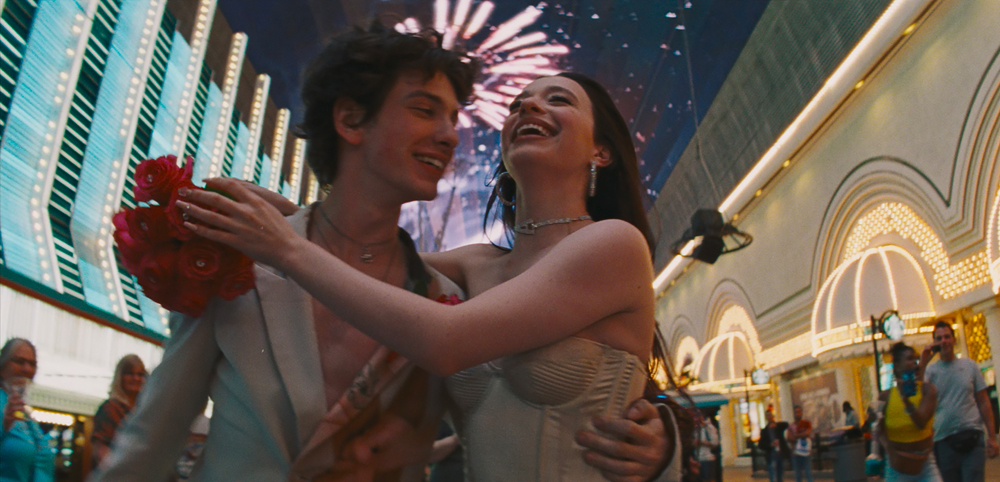 Dans le film Anora,Mikey Madison et Mark Eydelshteyn prennent la pose en souriant à Las Vegas.