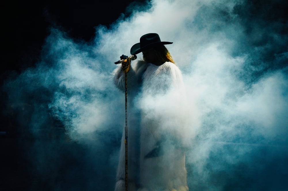 En concert à Paris, photo de la chanteuse Beyoncé en manteau blanc custom Burberry pendant un concert de sa tournée Cowboy Carter Tour.