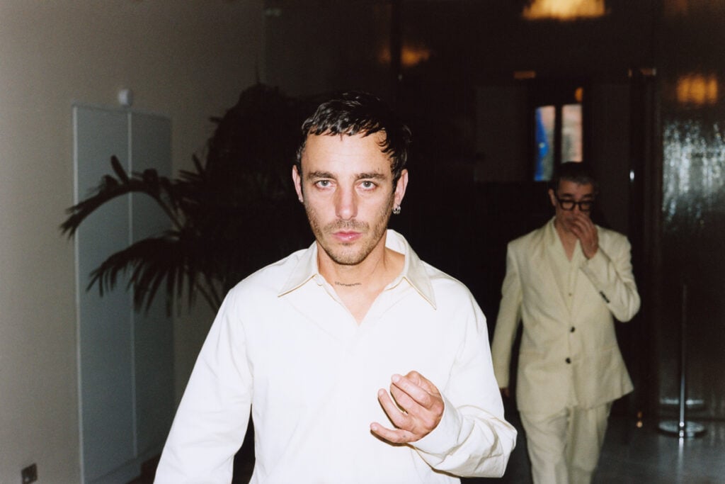 À gauche, Théo Mercier porte une chemise, Bottega Veneta.
À droite : veste et pantalon, Ami. Sweater, Zegna.