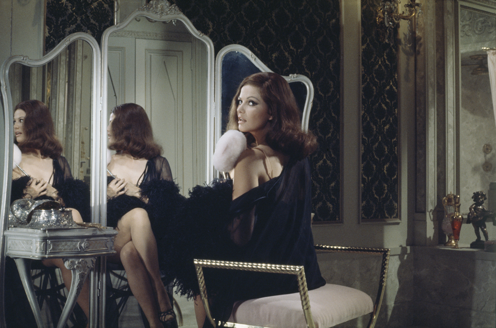 Claudia Cardinale, sur le tournage du film Au diable les héros vêtue d'une nuisette noir, assise devant un miroir, le 21 juillet 1967.