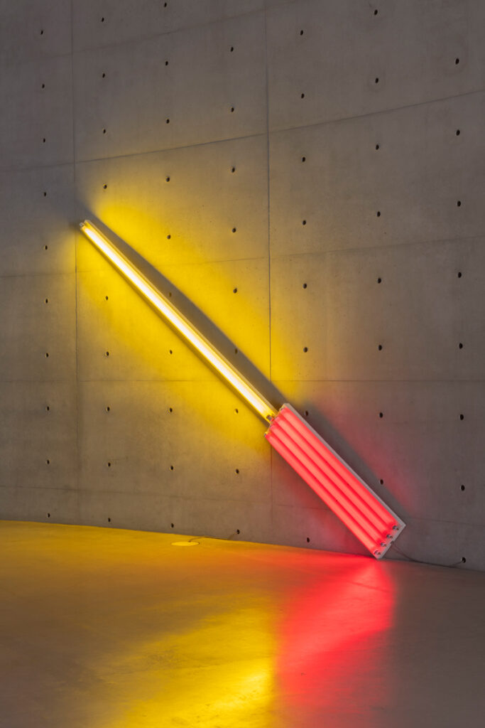 Dan Flavin, Alternate Diagonals of March 2 (1964) (to Don Judd) [1964]. Red and gold fluorescent light (Pinault Collection).<br>View of the exhibition “Minimal”, Bourse de commerce – Pinault Collection, Paris, 2025. © Tadao Ando Architect & Associates, Niney and Marca Architectes, Pierre-Antoine Gatier agency. Photo: Nicolas Brasseur / Pinault Collection.

