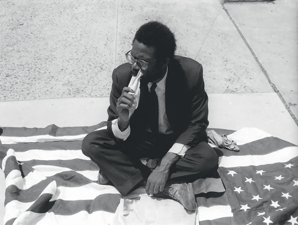 Pope.L, Eating the Wall Street Journal, 1991. Photographie : James Pruznick. Courtesy The Estate of Pope.L et Mitchell-Innes & Nash, New York © The Estate of Pope.L
