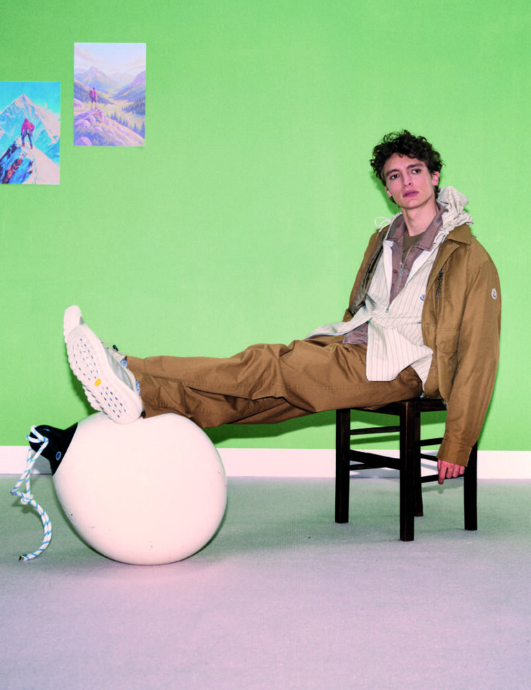 Vassili Schneider porte un blouson en twill technique, un coupe-vent à capuche en coton technique rayé, un blouson
zippé en coton délavé, un ee-shirt en jersey de coton, un pantalon en gabardine de coton, des chaussettes et des sneakers, MONCLER.