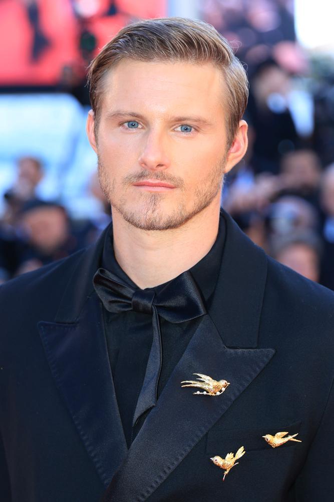 Alexander Ludwig lors de la projection du film Garance, avec un costume AMI noir et trois broches Chaumet