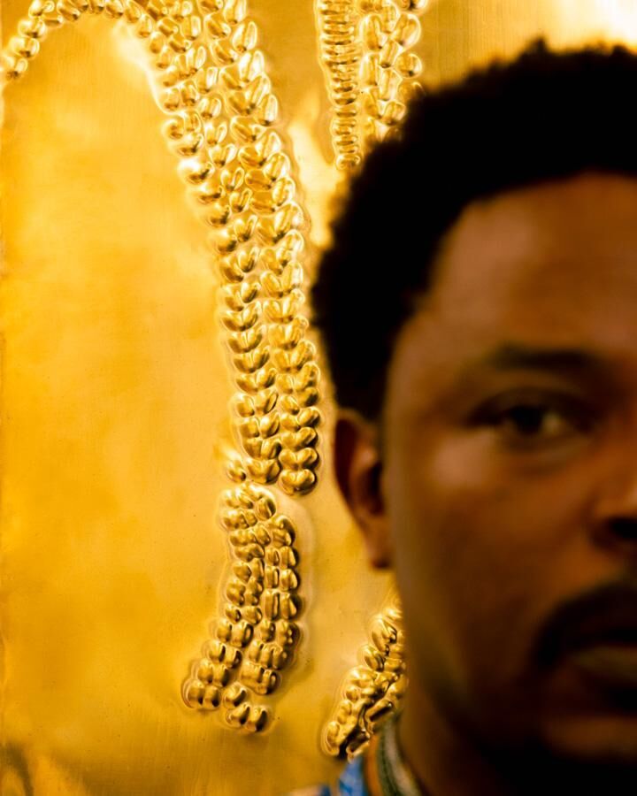 Sammy Baloji photographié par Deleli Ayivi avec une plaque de sa série Untitled (2015). Plaque de cuivre embossée, 60 × 42,5 cm. Courtesy the artist, galerie Imane Farès.