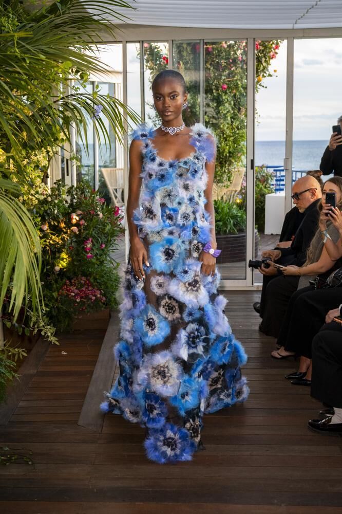 Une robe haute couture longue ornée de fleurs bleues du défilé Caroline's Couture 2026