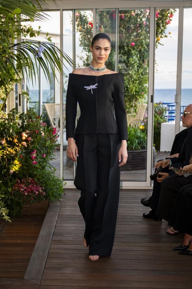 Une ensemble de tailleur noir, une broche en forme de libellule et un collier haute joaillerie du défilé Caroline's Couture 2026