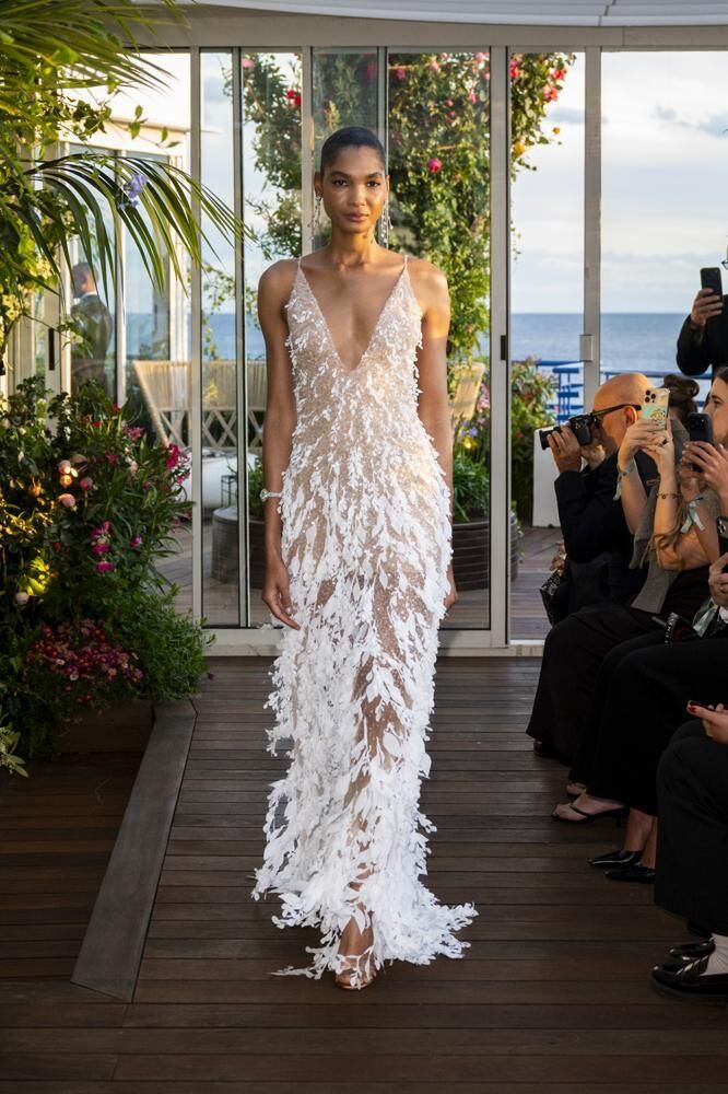 Une robe haute couture longue à fleurs blanches et à bretelles du défilé Caroline's Couture 2026