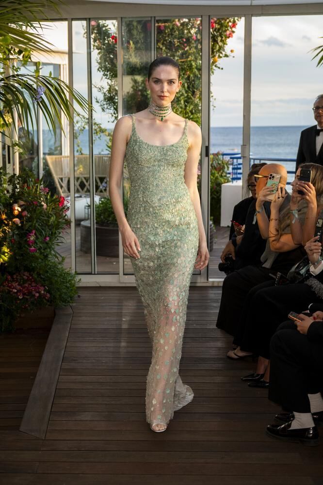 Une robe haute couture longue à bretelles et ornée de fleurs vertes du défilé Caroline's Couture 2026 avec un collier vert haute joaillerie