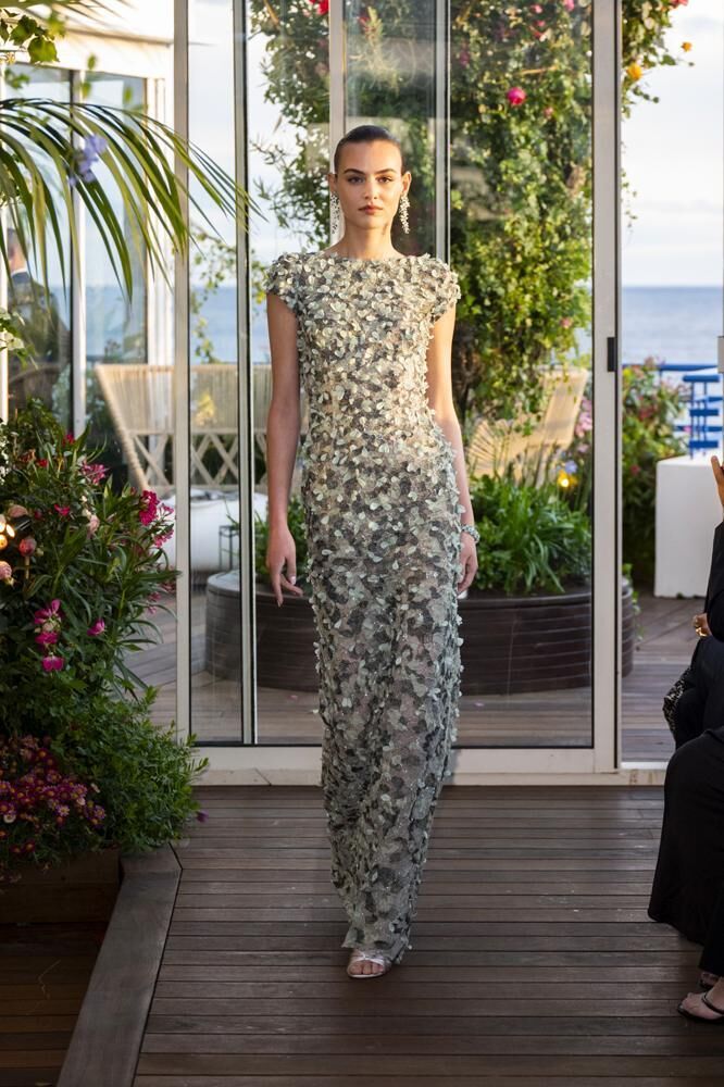 Une robe haute couture longue à manches courtes brodée de feuilles grises et vertes et des boucles d'oreilles haute joaillerie du défilé Caroline's Couture 2026