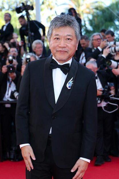 Le réalisateur Hirokazu Kore-eda avec une broche Chaumet en pierres précieuses bleues et en diamants.