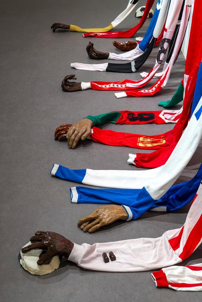 M'barka Amor, A portée de main, détail, 2026 © ADAGP Paris 2026. Onze maillots de football, onze étiquettes-poésies, mains et ballons en céramique et porcelaine. Crédits photo : Marc Domage