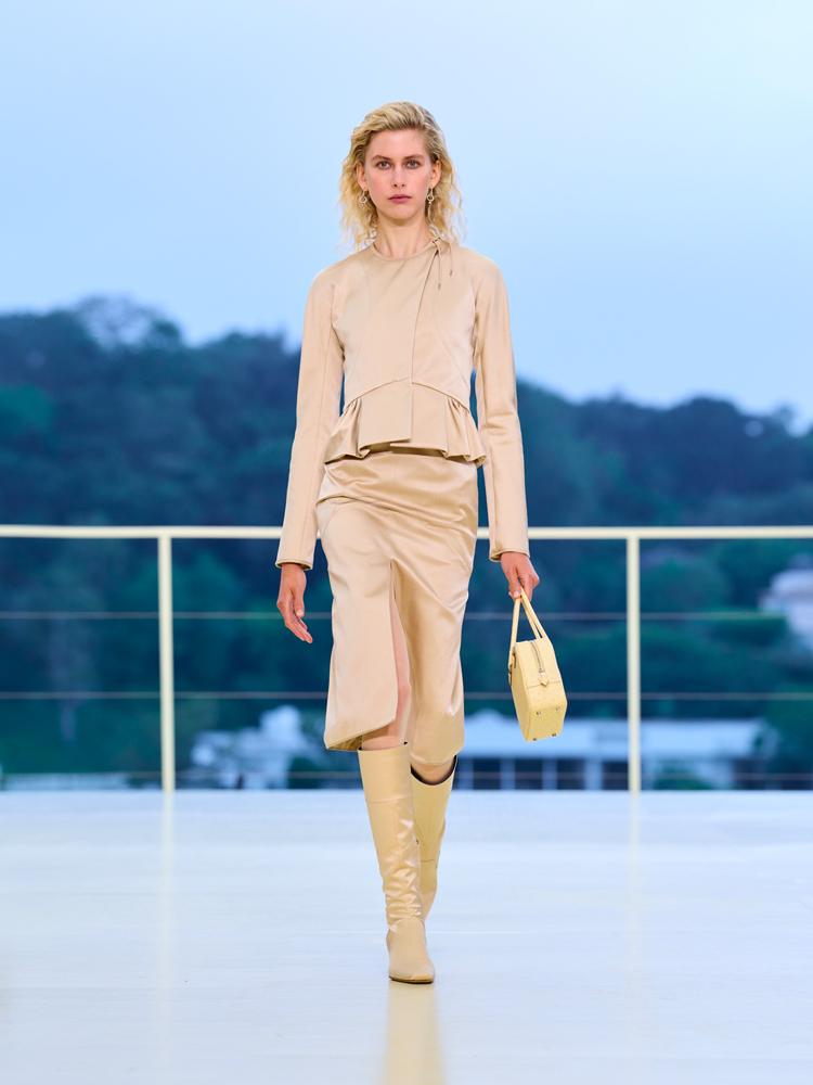 L'ensemble jupe et veste beige satiné, les bottes en cuir beiges et le sac en cuir beige du défilé automne-hiver 2026-2027 de Hermès à Los Angeles
