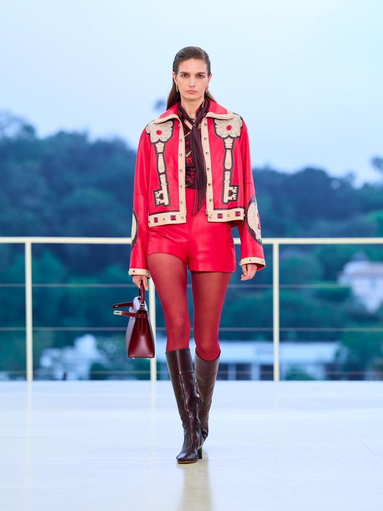 La veste en cuir à motifs rouge, le short en cuir rouge, les collants rouges, les bottes rouges et le sac Hermès Kelly rouge du défilé automne-hiver 2026-2027 de Hermès à Los Angeles